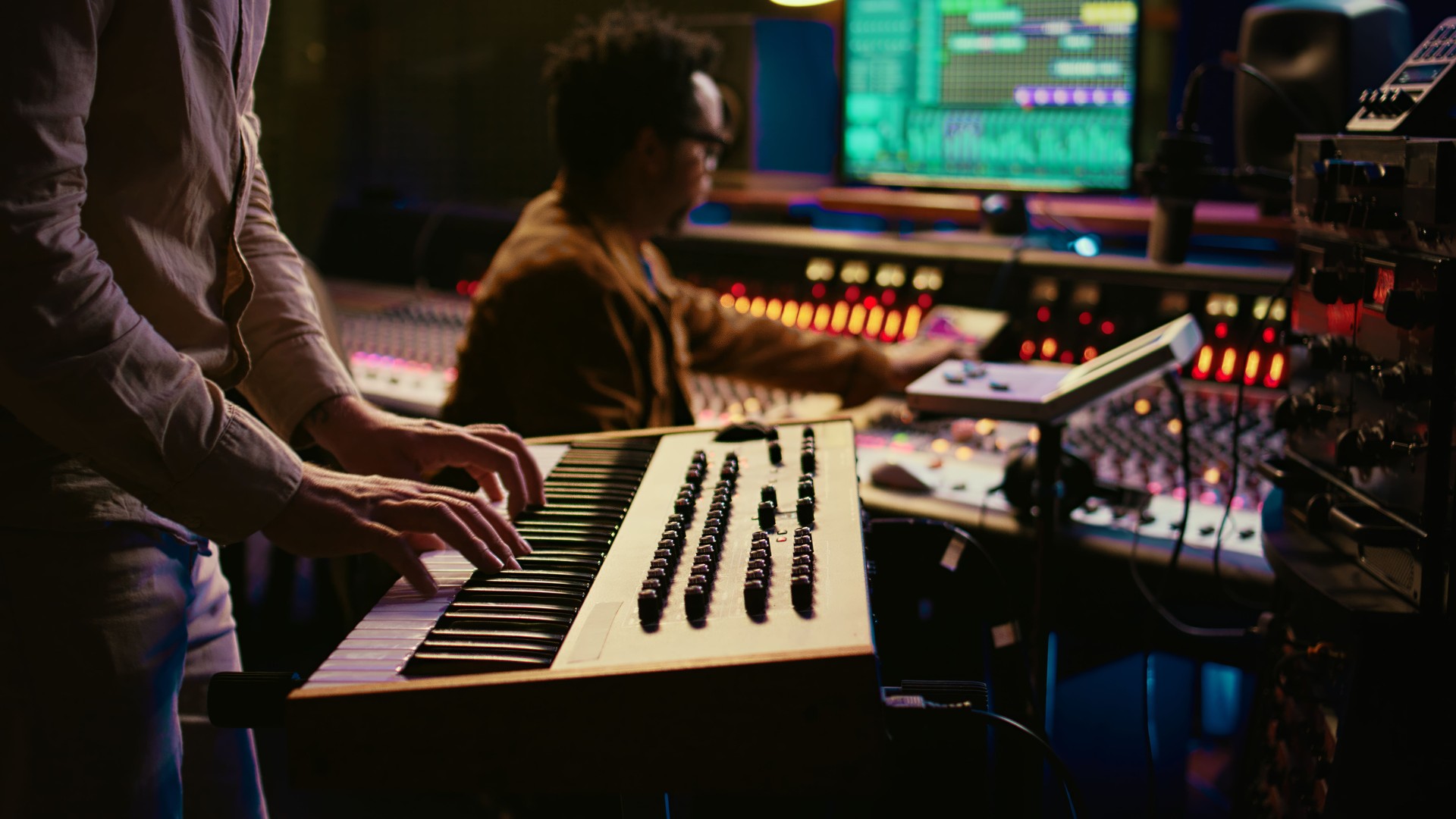 Musician playing piano midi controller in control room at recording studio