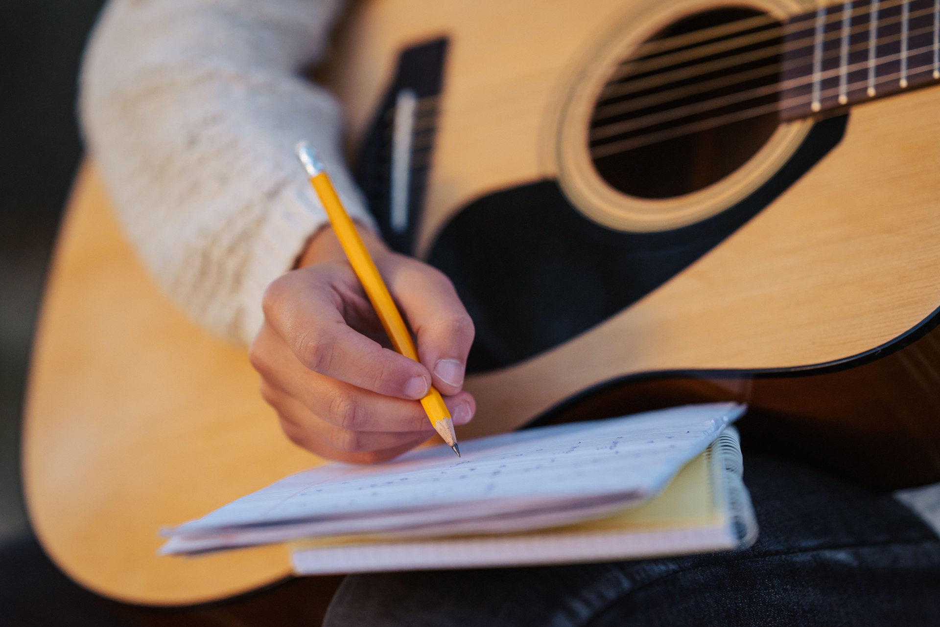 Close up of a girl musician composing song, writing down chords to the notes