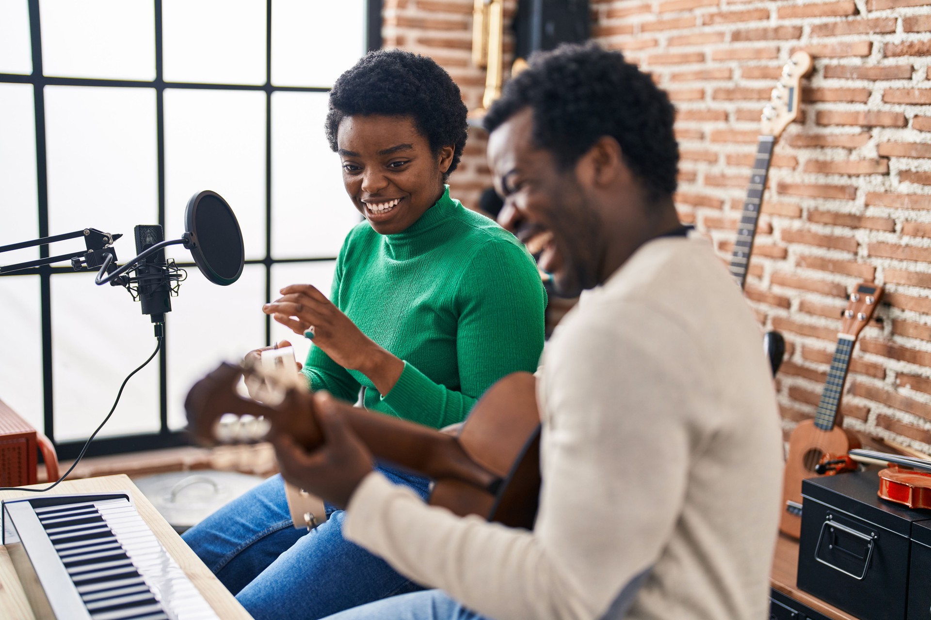 African american man and woman music group singing song playing guitar and tambourine at music studio